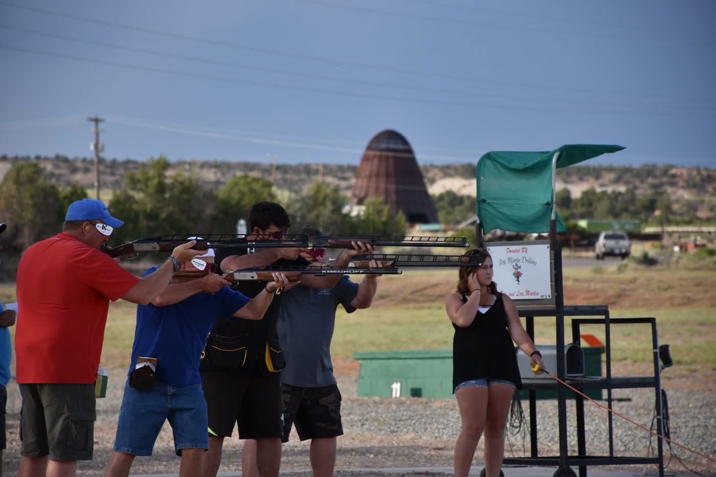 Four shooters lined up with shotguns at the ready, Krieghoffs over their shoulders.