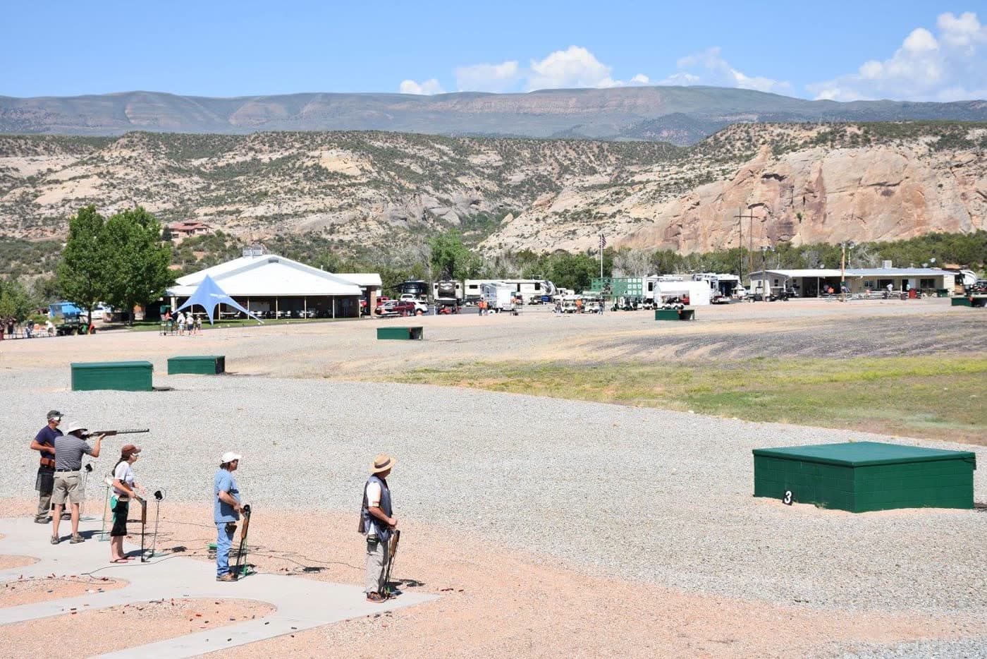 A wide line of shooters with the Uintah cliffs and the Lodge in the background.