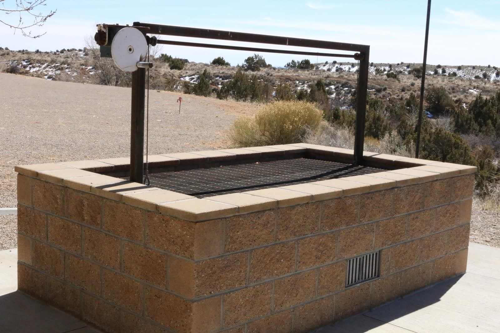 The outdoor brick BBQ pit with grill grate, set against the sage-and-snow Uintah landscape.